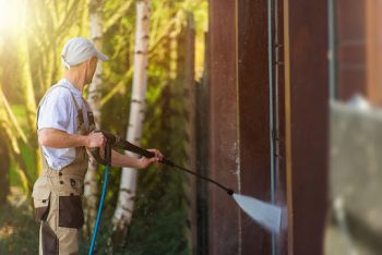 service technician performs power washing on a residential home
