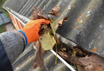 A man with orange gloves gutter cleaning