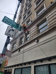 man on building performing commercial window cleaning