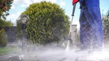 a man pressure washing a sidewalk